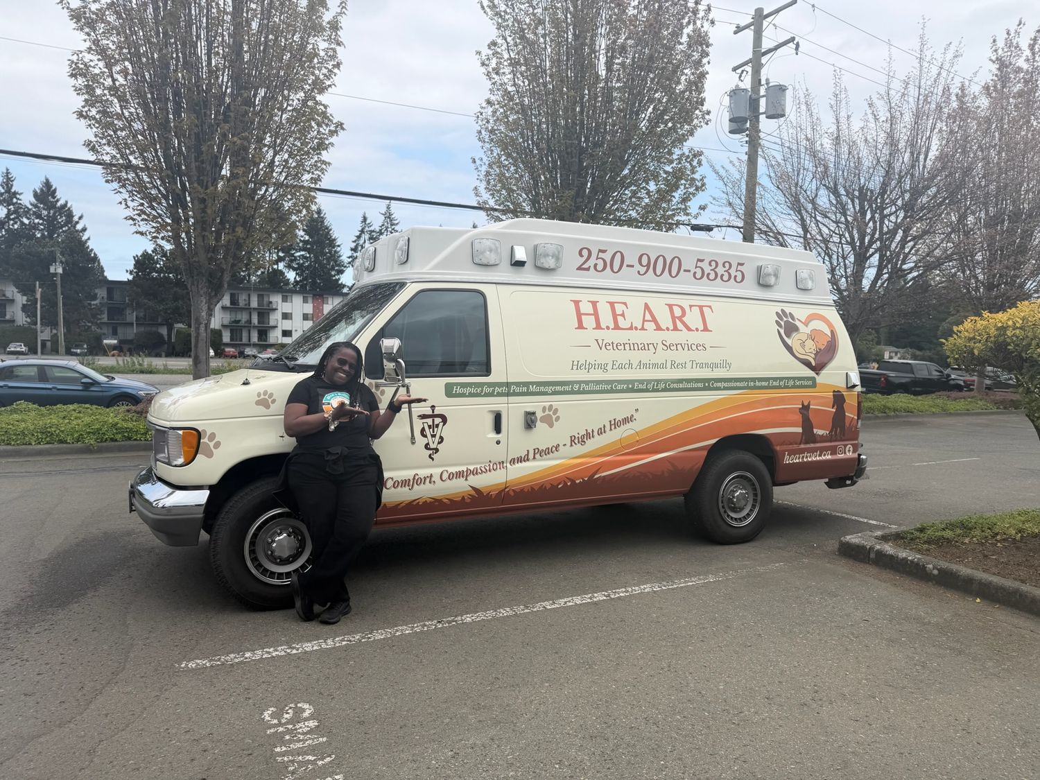 The H.E.A.R.T. Veterinary Services mobile clinic, fully wrapped, with Dr. Atkinson-Spinks standing beside it