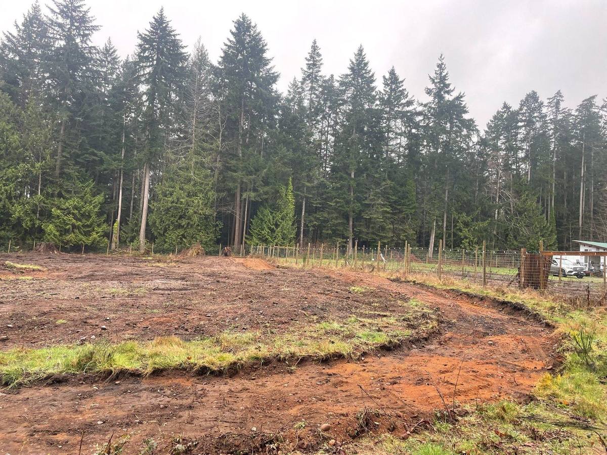Land cleared for the barn with perimeter fencing and forest behind